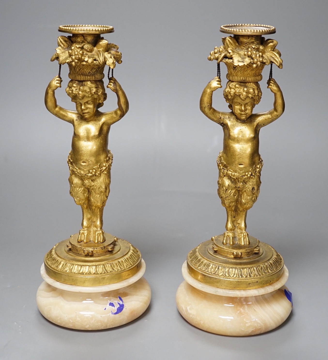 A pair of French gilt metal and onyx Bacchic faun candlesticks, 25.5 cms high